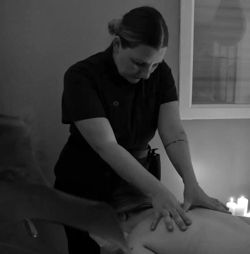 Stecy réalise un massage du dos lors d’une séance à domicile, en noir et blanc